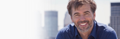 Мужчина в голубом свитере смотрит в камеру